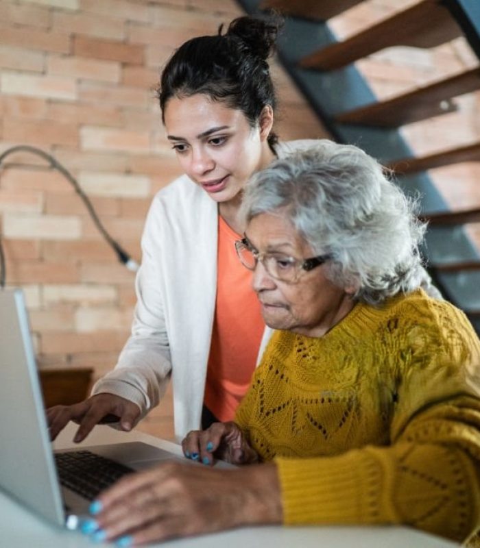 Granddaughter and grandmother using laptop at home